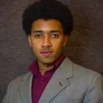 A man in a suit and tie standing up against a wall.