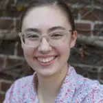 A woman with glasses smiling for the camera.