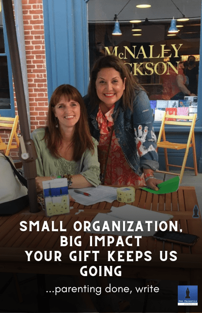 Two women sitting at a table with papers.