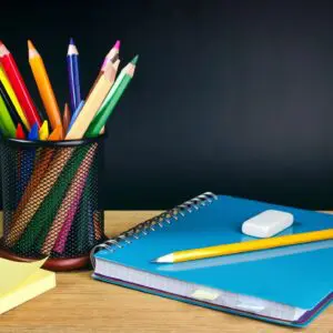 A blue notebook and some pencils on top of a table.