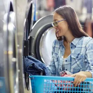 A woman is smiling while holding onto the laundry.