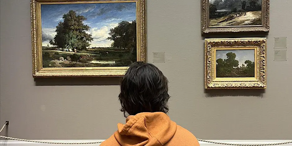 Person viewing landscape paintings in gallery.