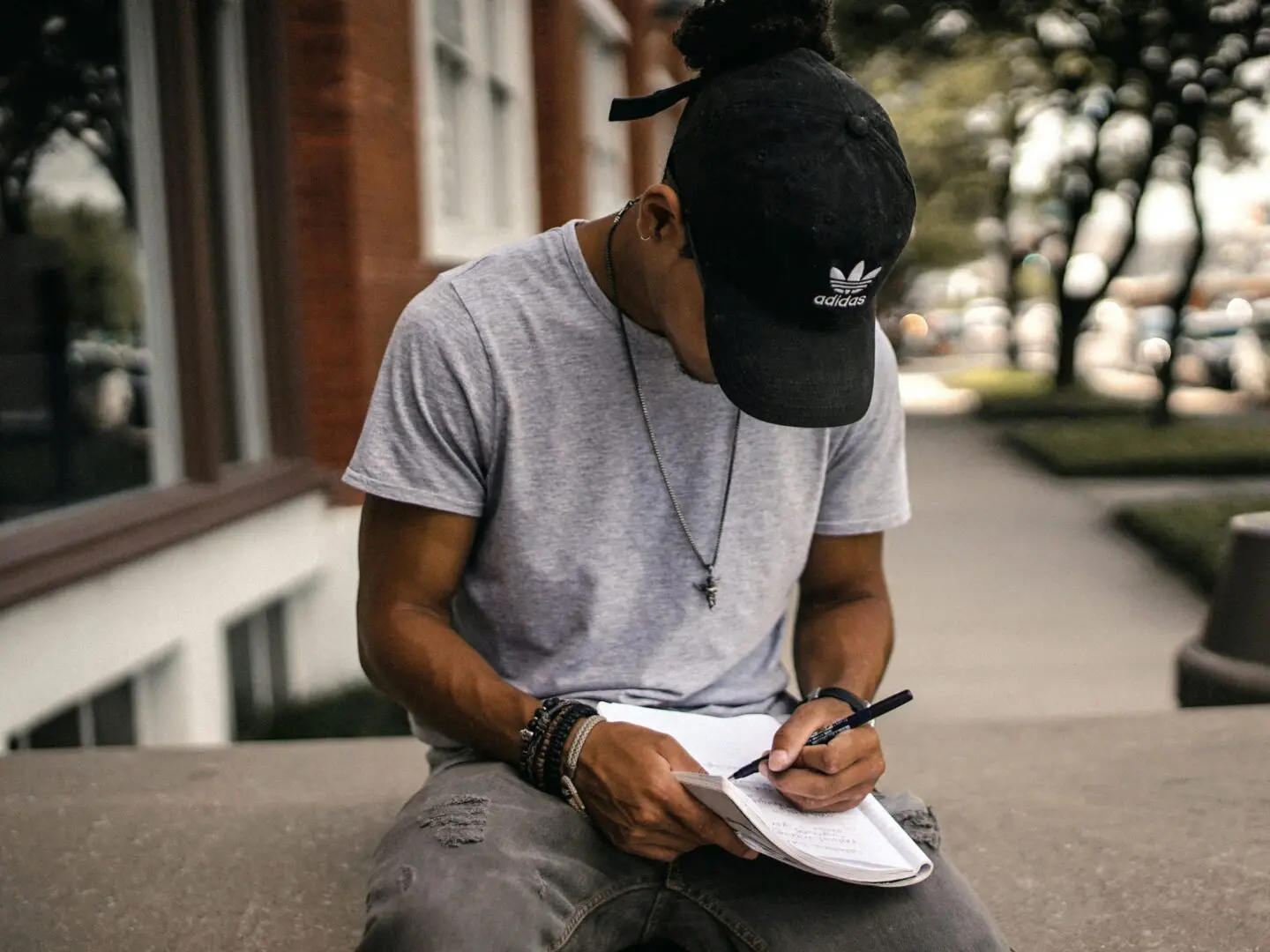 Man writing in notebook outdoors.