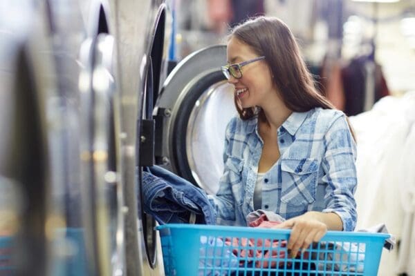 A woman is smiling while holding onto the laundry.