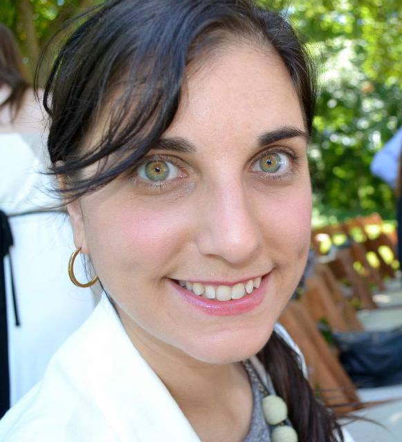 A woman with green eyes smiling for the camera.