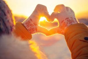 Heart-shaped hands, sunset glow.