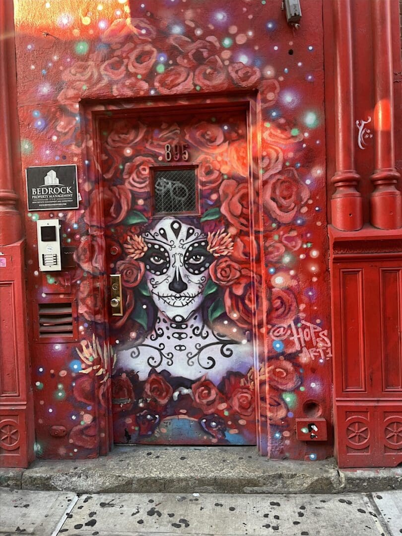 Red door with colorful skull mural artwork.