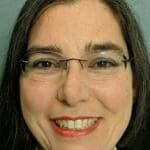 A woman with glasses smiling for the camera.