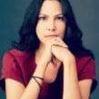 A woman with long black hair is sitting down