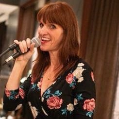 A woman with red hair is singing into a microphone.