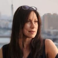 Woman with sunglasses on head, city background.