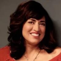 Smiling woman with dark hair, wearing necklace.