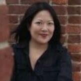 Woman standing by a brick wall.